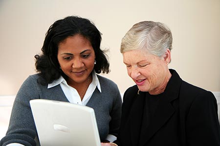 Woman helping another woman with a computer